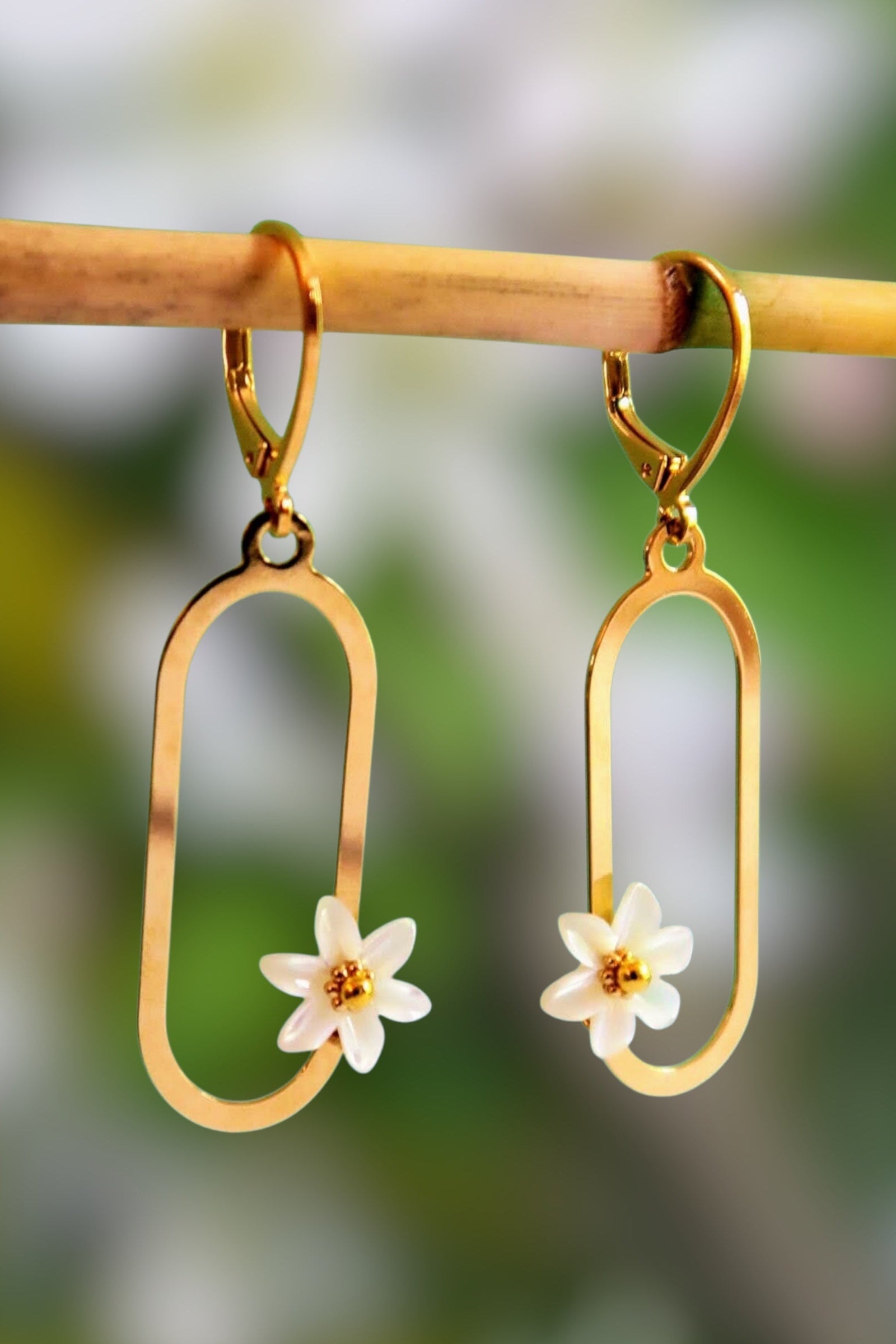 boucles d'oreilles pendantes de forme ovales avec des fleurs en nacre blanche et dorées. Modèle : Francesca