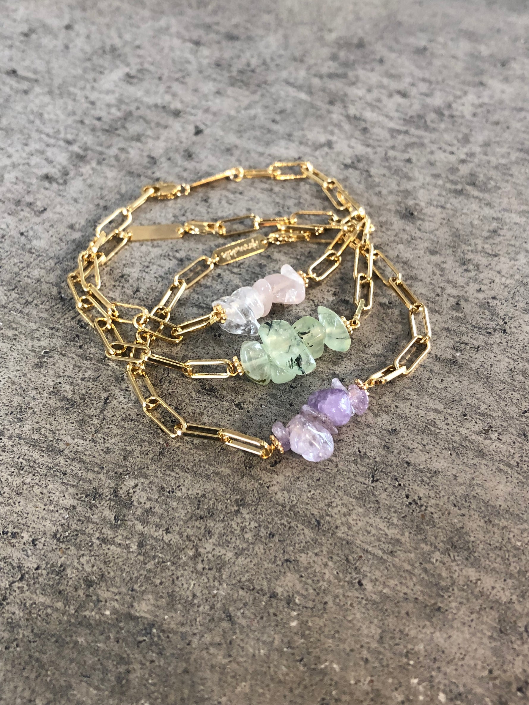 bracelets en trois couleurs de pierres différentes, vertes, roses ou violettes pales sur une chaine géométrique dorée