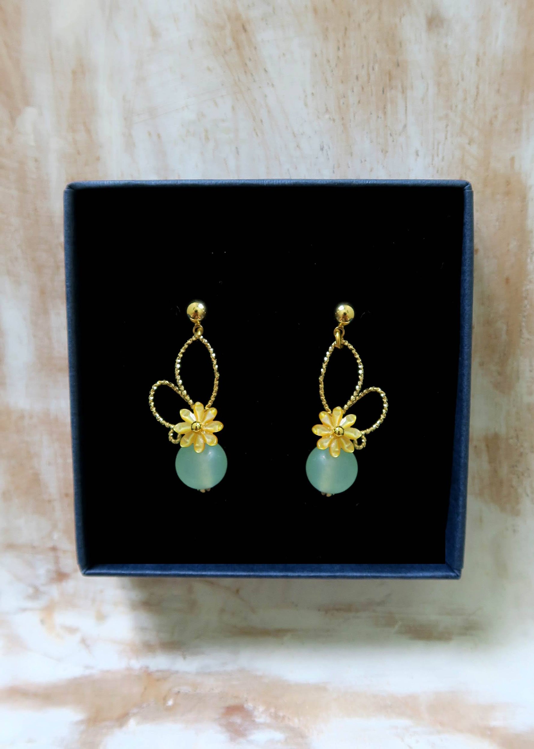 boucles d'oreilles fleur nacre jaune et jade vert dans un ecrin