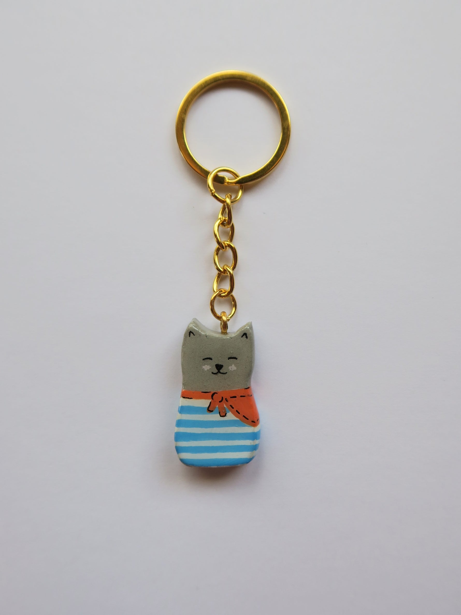 Porte-clé Lucky Rolie Cat Eddy — petit chat gris breton espiègle en marinière, modelé et peint à la main en argile, fini à la résine UV. Pièce unique fait main en Bretagne.