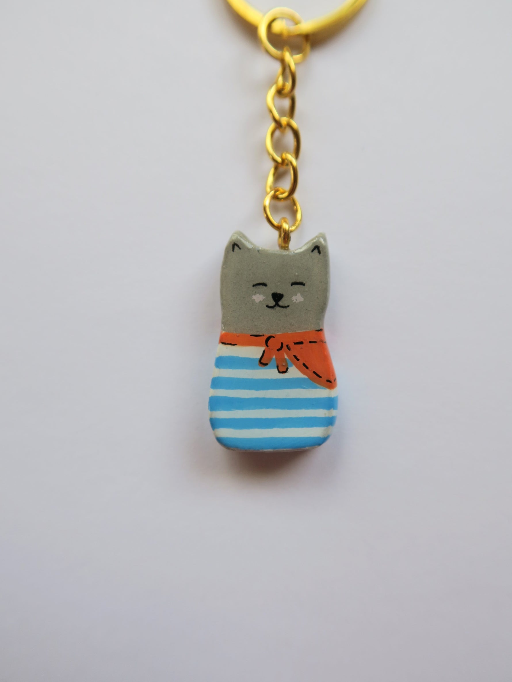 Porte-clé Lucky Rolie Cat Eddy — petit chat gris breton espiègle en marinière, modelé et peint à la main en argile, fini à la résine UV. Pièce unique fait main en Bretagne.