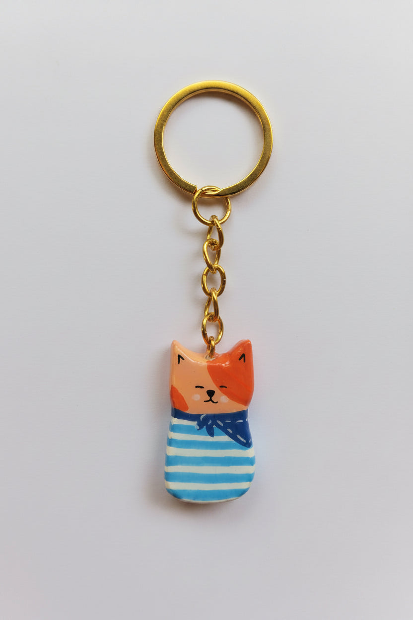 Porte-clé Lucky Rolie Cat Émile — petit chat roux breton malicieux en marinière, modelé et peint à la main en argile, fini à la résine UV. Pièce unique fait main en Bretagne.