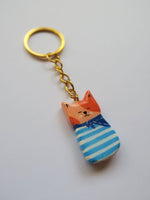 Porte-clé Lucky Rolie Cat Émile — petit chat roux breton malicieux en marinière, modelé et peint à la main en argile, fini à la résine UV. Pièce unique fait main en Bretagne.