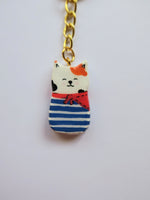Porte-clé Lucky Rolie Cat Gwendal — petit chat tricolore breton en marinière bleu marine, modelé et peint à la main en argile, fini à la résine UV. Pièce unique fait main en Bretagne.