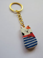 Porte-clé Lucky Rolie Cat Gwendal — petit chat tricolore breton en marinière bleu marine, modelé et peint à la main en argile, fini à la résine UV. Pièce unique fait main en Bretagne.