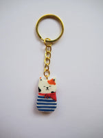 Porte-clé Lucky Rolie Cat Gwendal — petit chat tricolore breton en marinière bleu marine, modelé et peint à la main en argile, fini à la résine UV. Pièce unique fait main en Bretagne.