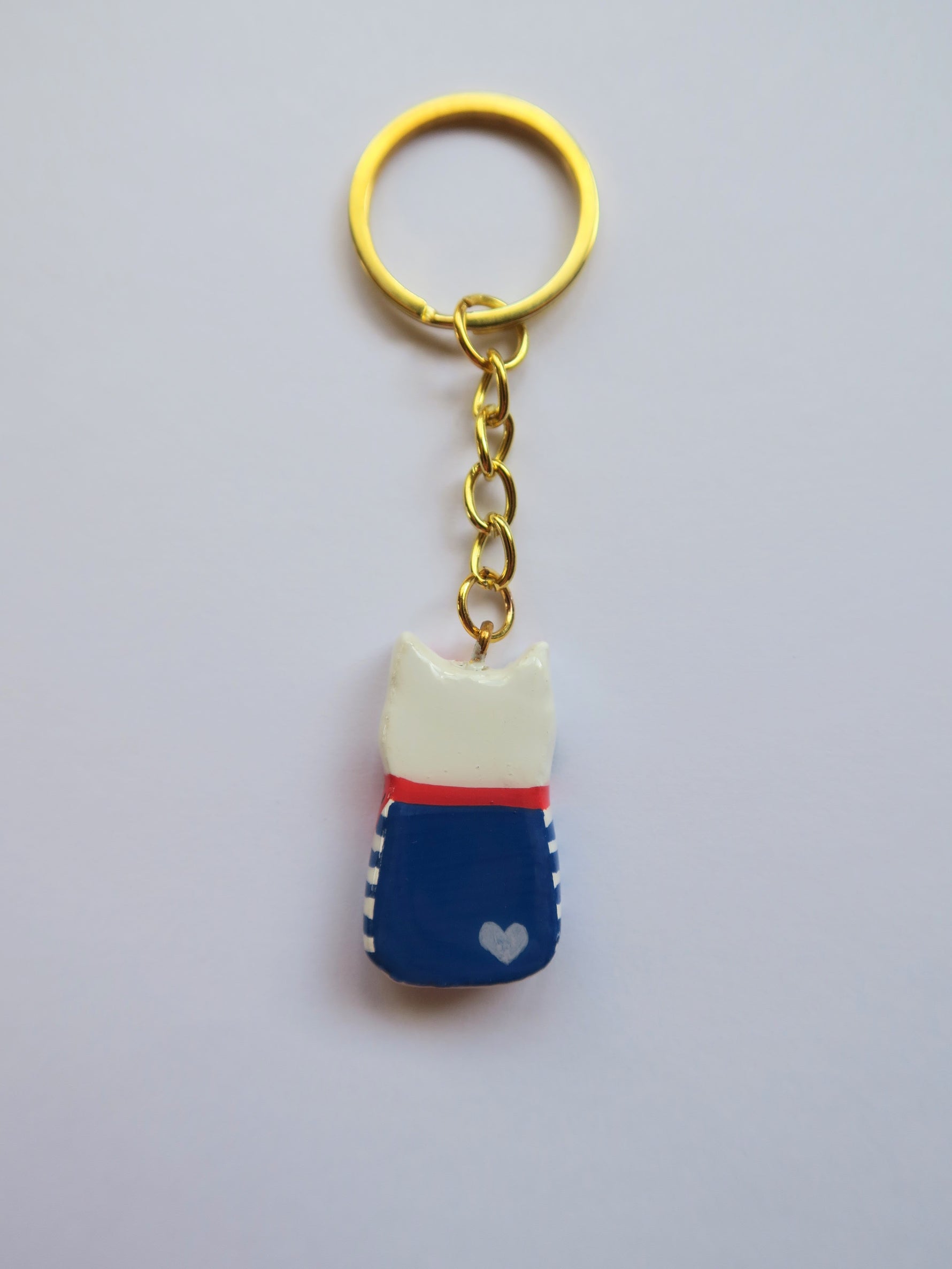 Porte-clé Lucky Rolie Cat Gwendal — petit chat tricolore breton en marinière bleu marine, modelé et peint à la main en argile, fini à la résine UV. Pièce unique fait main en Bretagne.