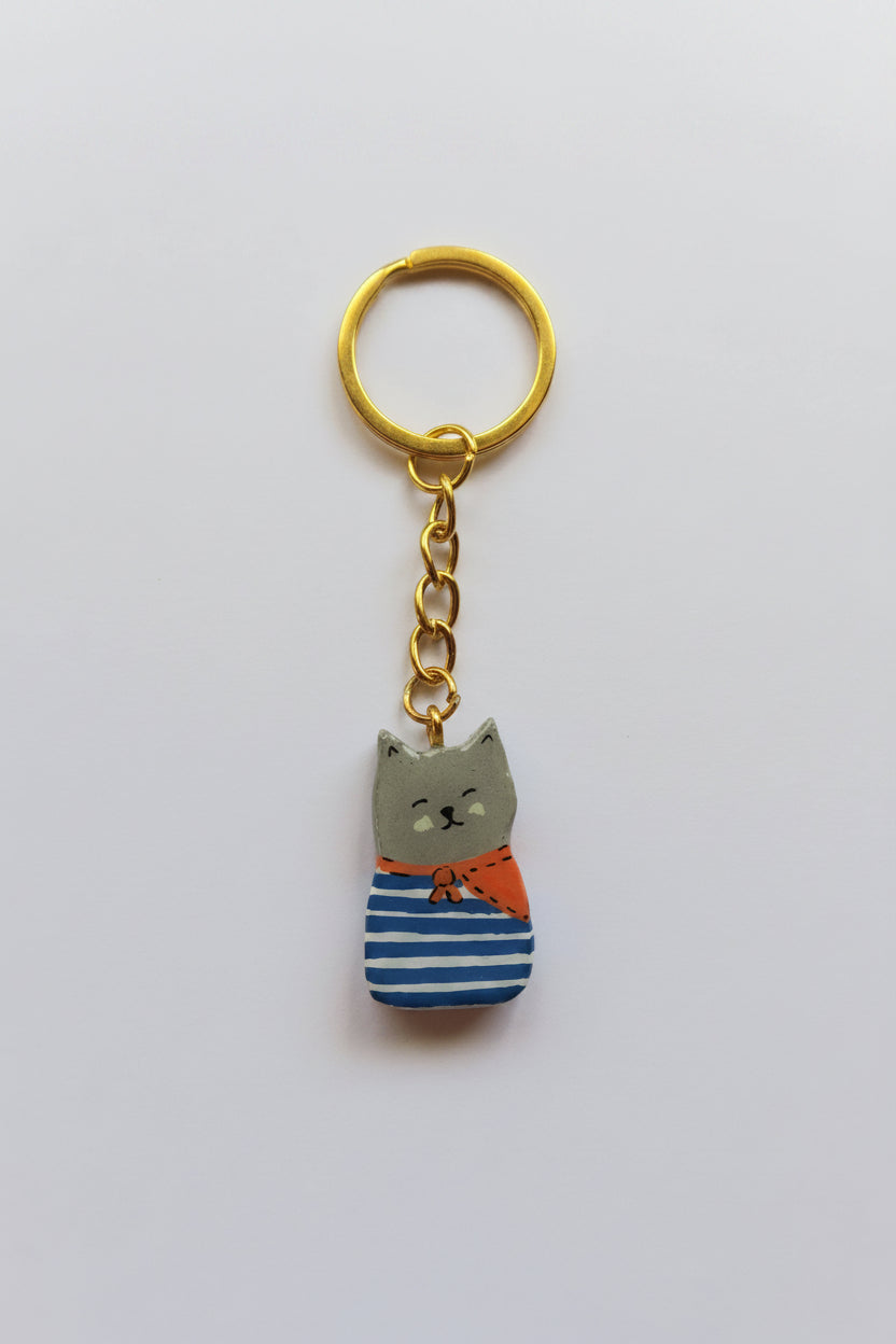 Porte-clé Lucky Rolie Cat Martin — petit chat gris breton en marinière, modelé et peint à la main en argile, fini à la résine UV. Pièce unique fait main en Bretagne.