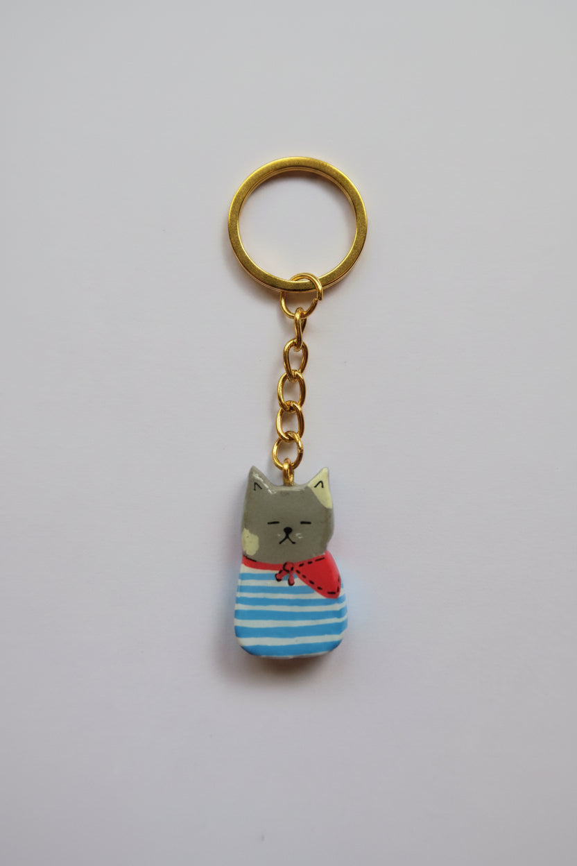 Porte-clé Lucky Rolie Cat Paul — petit chat gris breton en marinière, modelé et peint à la main en argile, fini à la résine UV. Pièce unique fait main en Bretagne.
