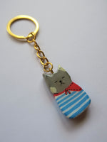 Porte-clé Lucky Rolie Cat Paul — petit chat gris breton en marinière, modelé et peint à la main en argile, fini à la résine UV. Pièce unique fait main en Bretagne.