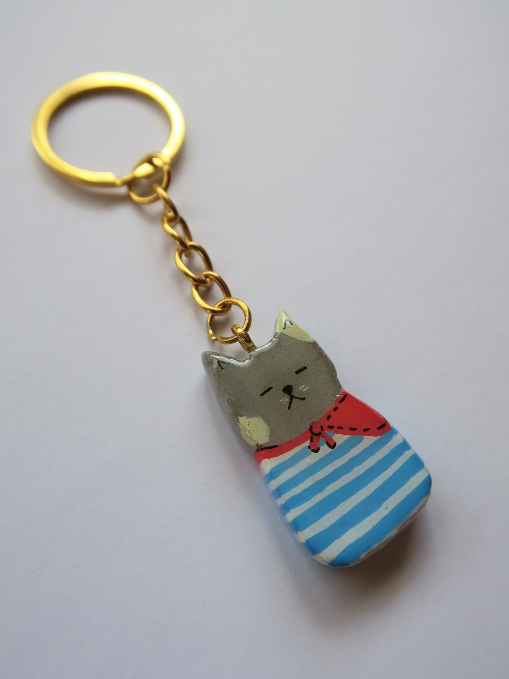 Porte-clé Lucky Rolie Cat Paul — petit chat gris breton en marinière, modelé et peint à la main en argile, fini à la résine UV. Pièce unique fait main en Bretagne.