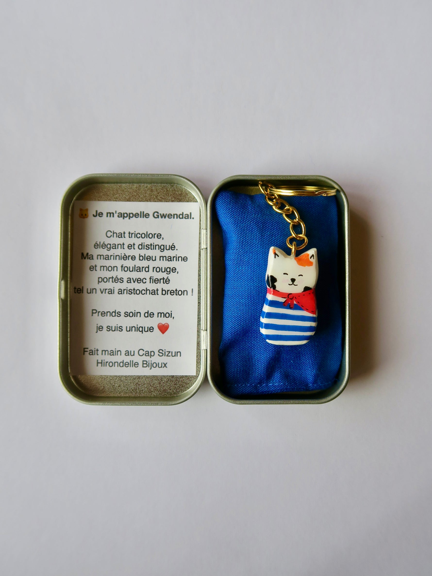 Porte-clé Lucky Rolie Cat Gwendal — petit chat tricolore breton en marinière bleu marine, modelé et peint à la main en argile, fini à la résine UV. Pièce unique fait main en Bretagne.