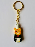 Porte-clé Lucky Rolie Cat Soizic — chatte bigoudène rousse en costume traditionnel, modelée et peinte à la main en argile, finie à la résine UV. Fait main au Cap Sizun.