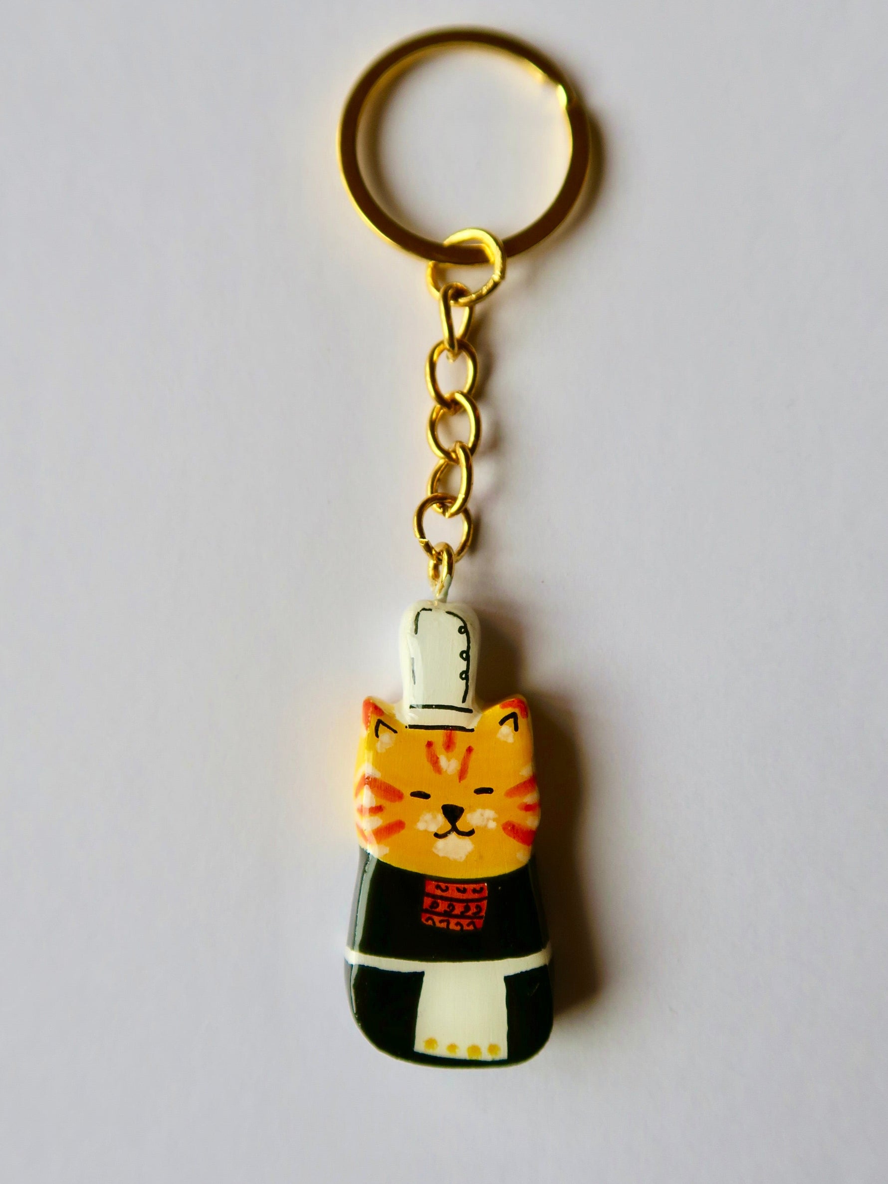 Porte-clé Lucky Rolie Cat Soizic — chatte bigoudène rousse en costume traditionnel, modelée et peinte à la main en argile, finie à la résine UV. Fait main au Cap Sizun.