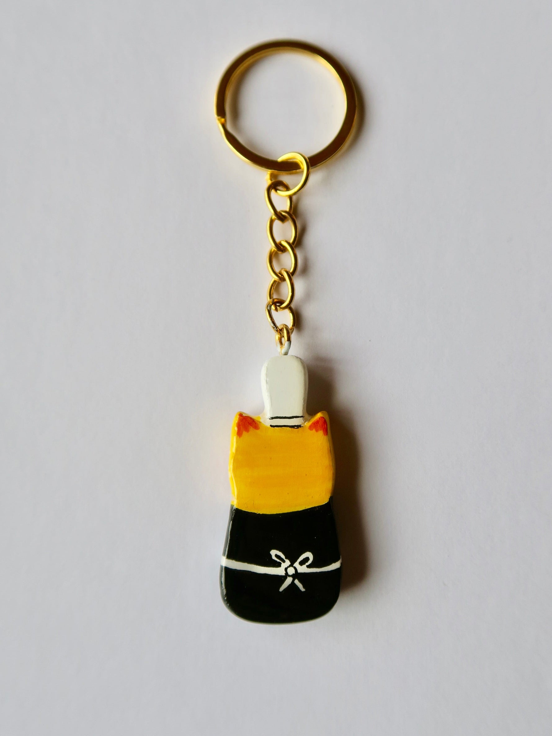 Porte-clé Lucky Rolie Cat Soizic — chatte bigoudène rousse en costume traditionnel, modelée et peinte à la main en argile, finie à la résine UV. Fait main au Cap Sizun.