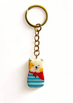 Porte-clé Lucky Rolie Cat Loïc — petit chat blanc breton joyeux en marinière, modelé et peint à la main en argile, fini à la résine UV. Pièce unique fait main en Bretagne.
