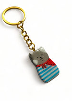 Porte-clé Lucky Rolie Cat Paul — petit chat gris breton en marinière, modelé et peint à la main en argile, fini à la résine UV. Pièce unique fait main en Bretagne.