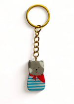 Porte-clé Lucky Rolie Cat Paul — petit chat gris breton en marinière, modelé et peint à la main en argile, fini à la résine UV. Pièce unique fait main en Bretagne.