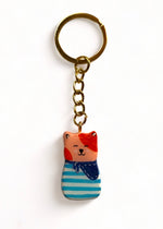 Porte-clé Lucky Rolie Cat Émile — petit chat roux breton malicieux en marinière, modelé et peint à la main en argile, fini à la résine UV. Pièce unique fait main en Bretagne.