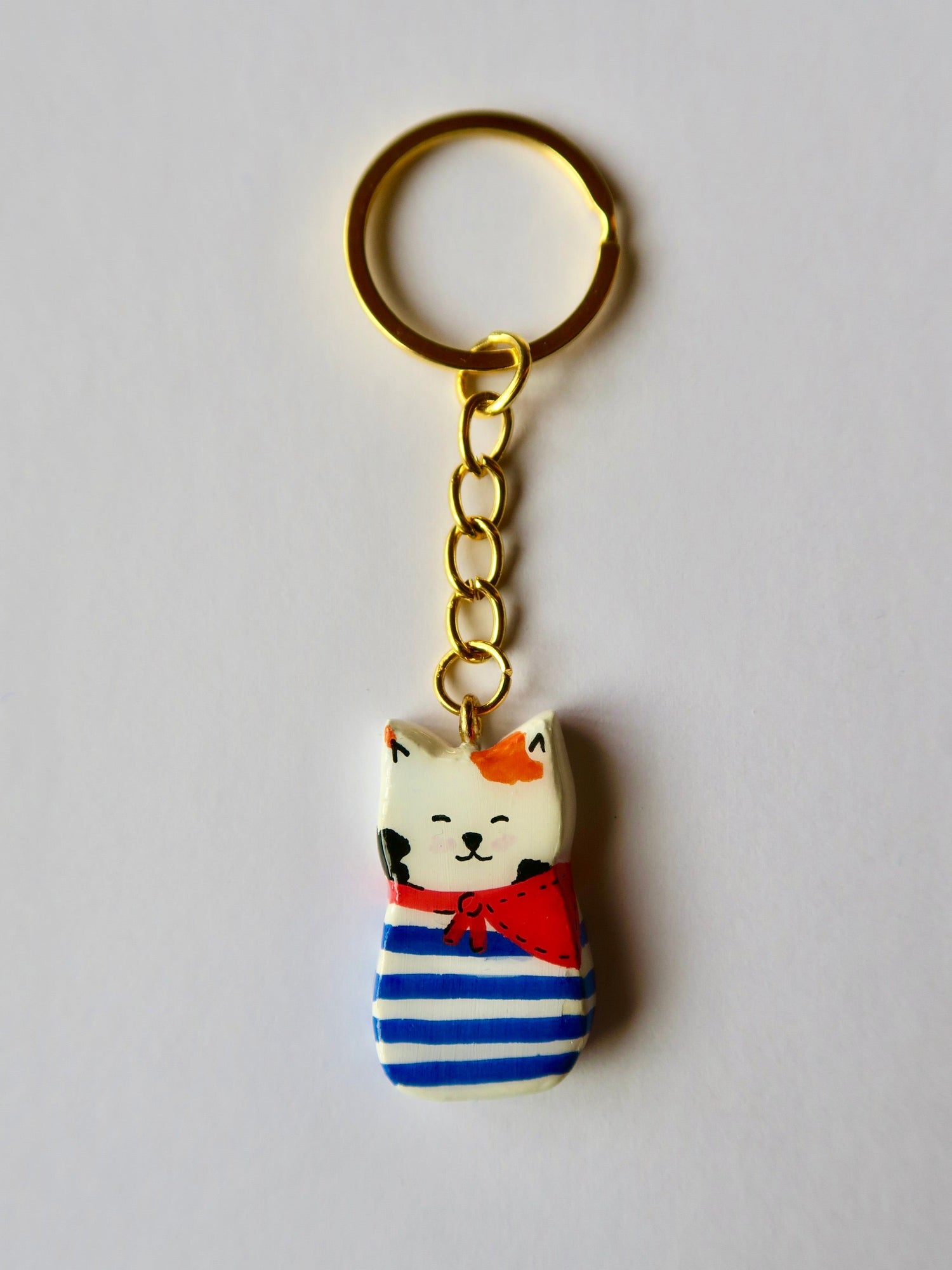 Porte-clé Lucky Rolie Cat Gwendal — petit chat tricolore breton en marinière bleu marine, modelé et peint à la main en argile, fini à la résine UV. Pièce unique fait main en Bretagne.