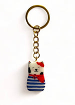 Porte-clé Lucky Rolie Cat Gwendal — petit chat tricolore breton en marinière bleu marine, modelé et peint à la main en argile, fini à la résine UV. Pièce unique fait main en Bretagne.