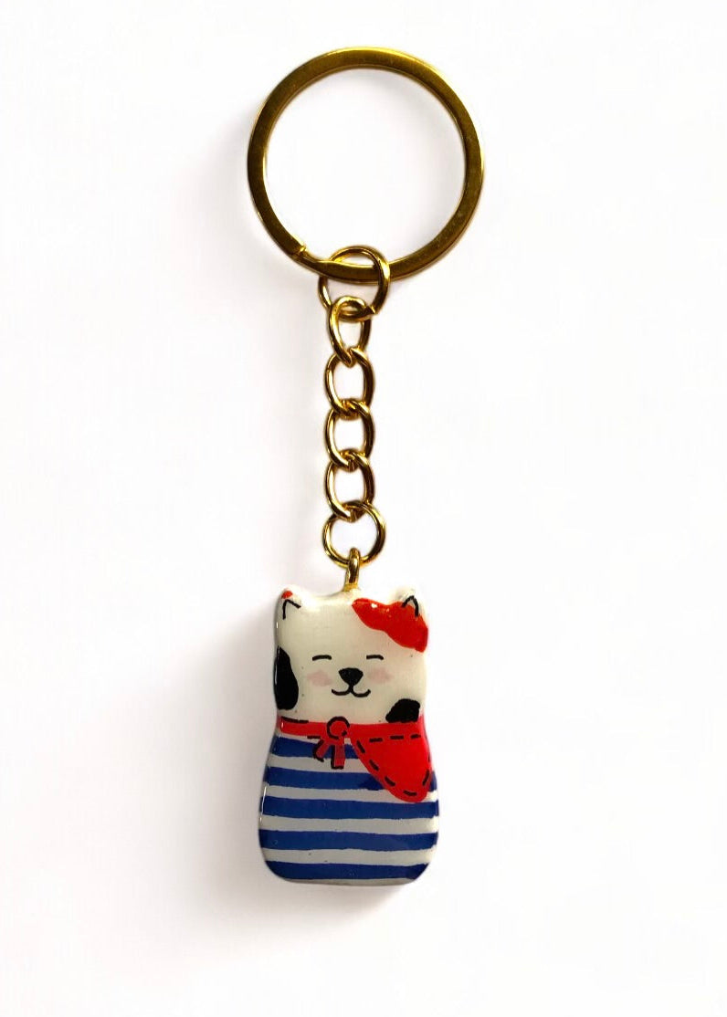 Porte-clé Lucky Rolie Cat Gwendal — petit chat tricolore breton en marinière bleu marine, modelé et peint à la main en argile, fini à la résine UV. Pièce unique fait main en Bretagne.