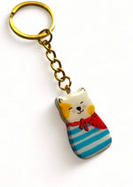 Porte-clé Lucky Rolie Cat Loïc — petit chat blanc breton joyeux en marinière, modelé et peint à la main en argile, fini à la résine UV. Pièce unique fait main en Bretagne.