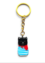 Porte-clé Lucky Rolie Cat Gabin — petit chat noir breton en marinière bleue et foulard rouge, modelé et peint à la main en argile, fini à la résine UV. Fait main au Cap Sizun.