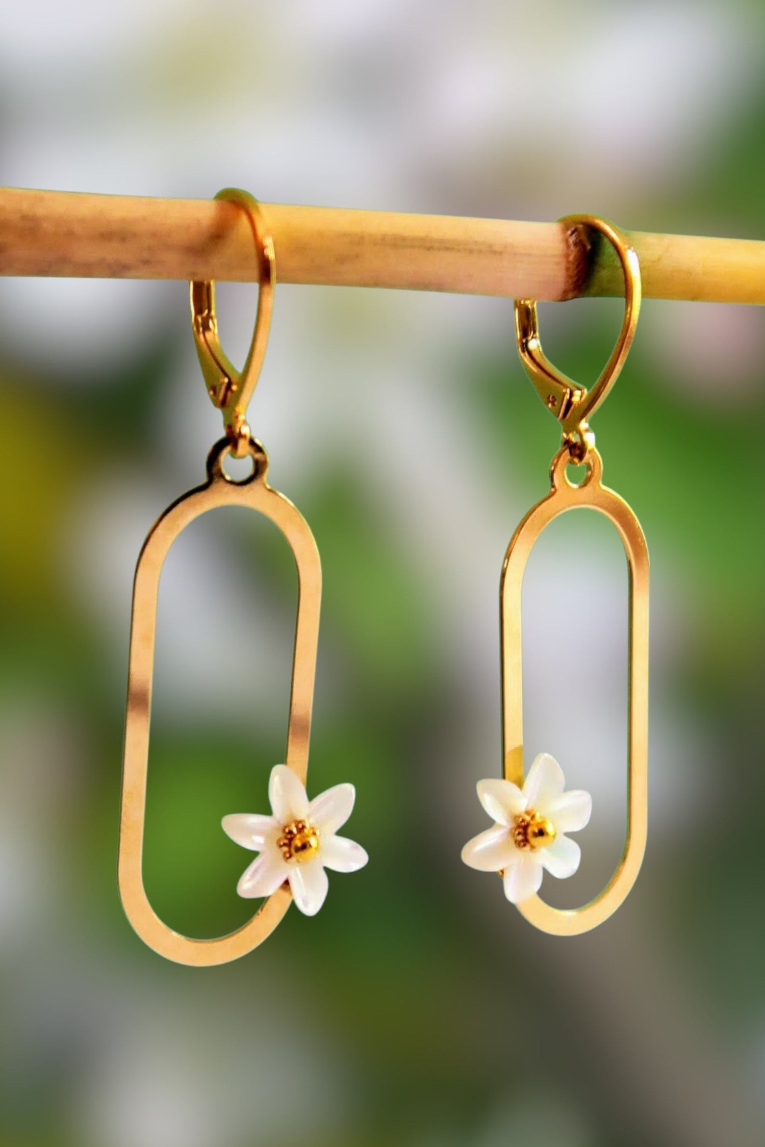 boucles d'oreilles pendantes de forme ovales avec des fleurs en nacre blanche et dorées. Modèle : Francesca