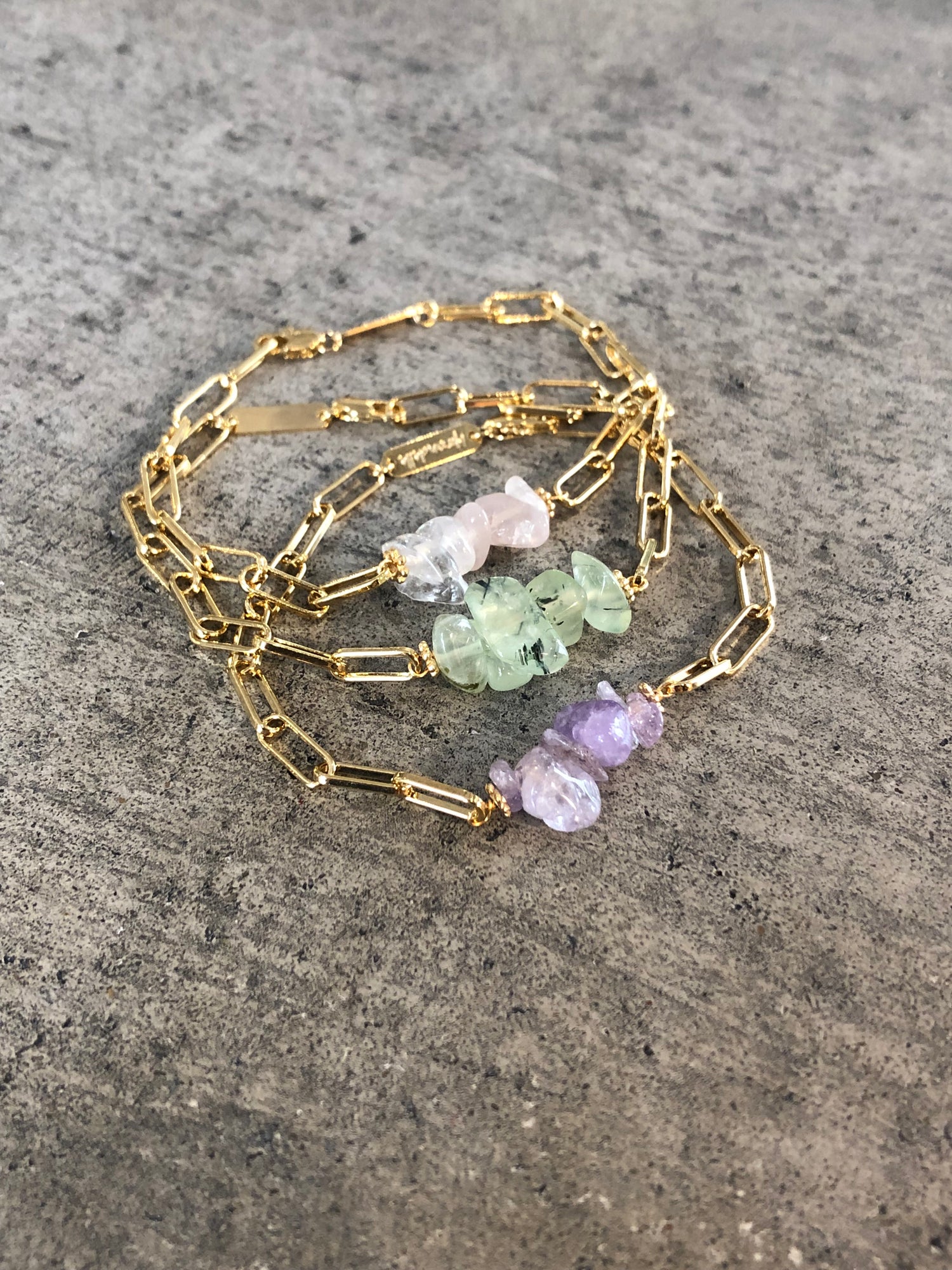 bracelets en trois couleurs de pierres différentes, vertes, roses ou violettes pales sur une chaine géométrique dorée