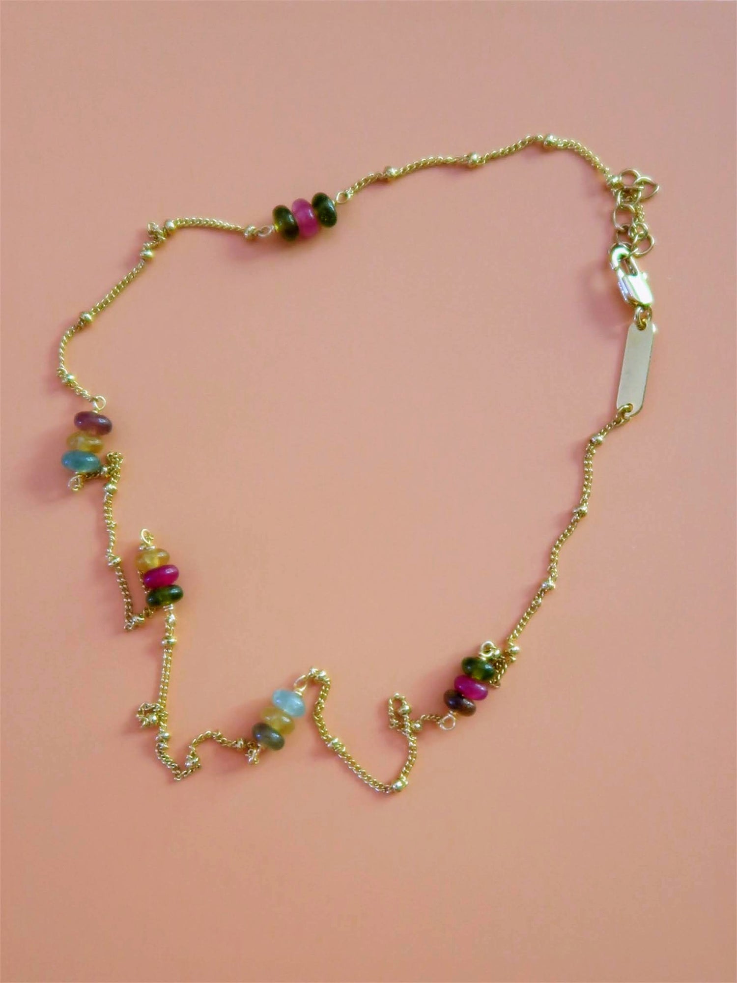 collier confettis posé sur un fond rose